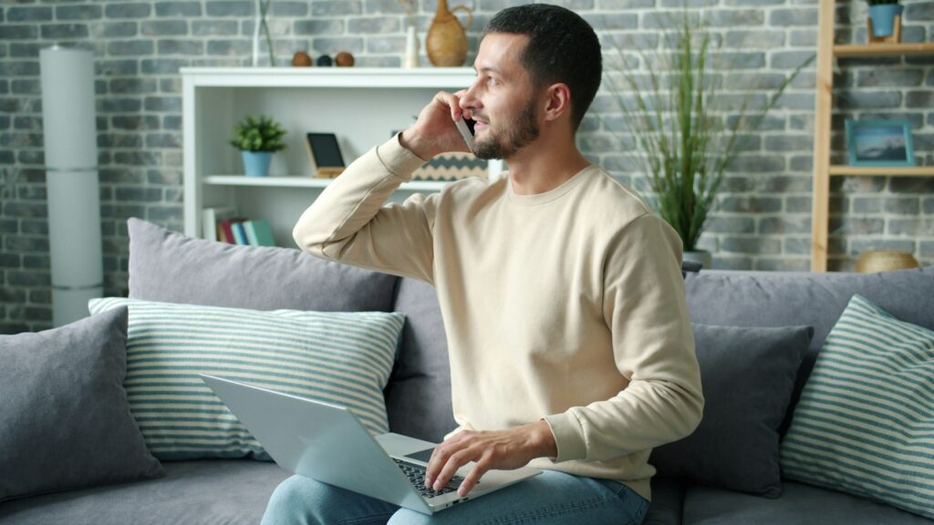 Advogado golpe de investimento: homem ao celular com notebook acompanha plataforma falsa